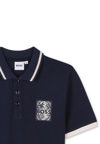 Marine poloshirt van een gestructureerde stof, met een crèmekleurige gestreepte kraag, drie knopen en een logopatch met palmboomsymbolen.