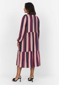 Robe maxi avec des rayures verticales en rose, marine et bordeaux. Manches longues, jupe à volants et coupe décontractée. Porter avec des talons noirs.