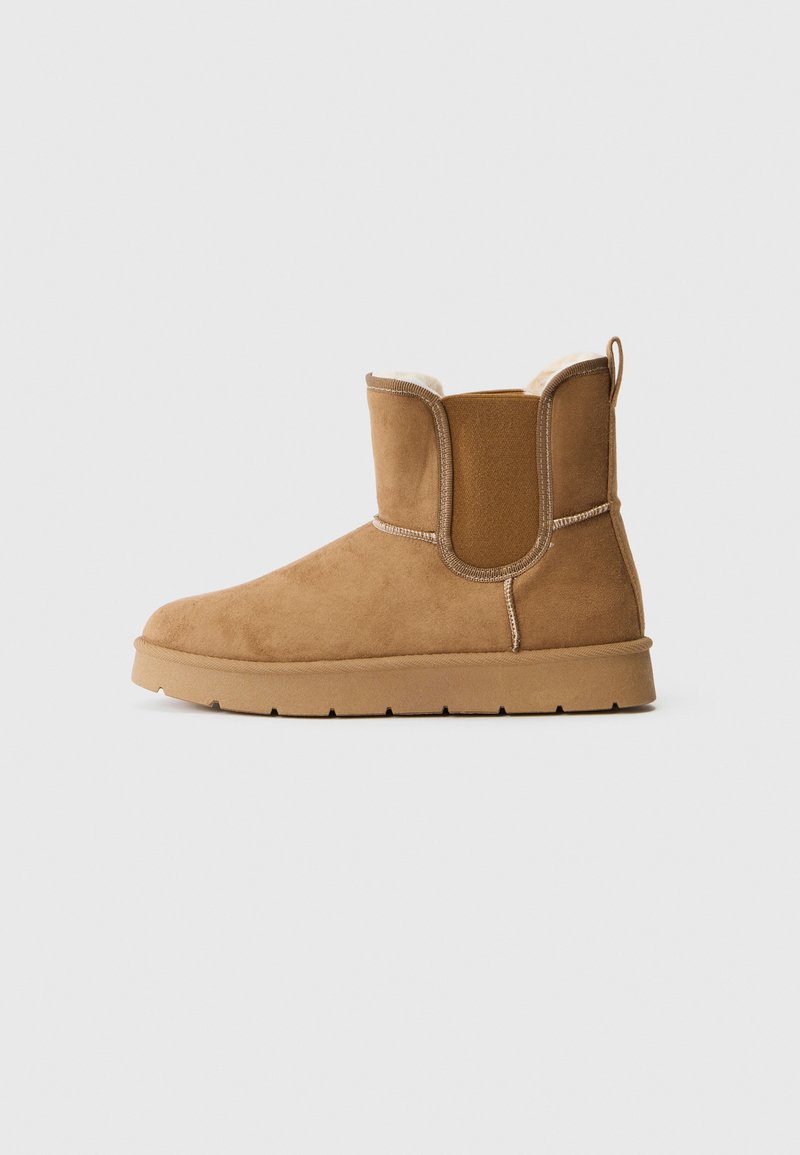 Mid-height tan suede boot with elastic side panels, rubber sole, pull tab, and soft, light-colored inner lining.