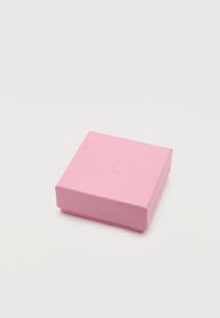 Μικρό ροζ τετράγωνο κουτί με υφή και ανάγλυφο λογότυπο κύκνου στην κορυφή, τοποθετημένο σε απλή λευκή επιφάνεια.