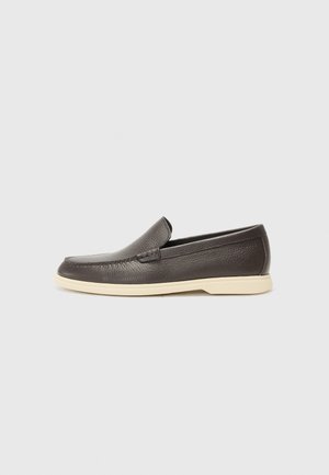 Brown leather slip-on shoes with a textured surface and a contrasting light beige sole, featuring a rounded toe and minimal stitching details.
