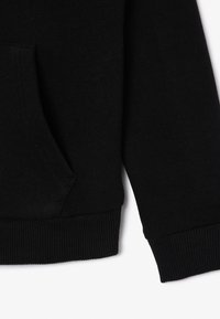 Zwarte hoodie van zacht materiaal met een voorzak, geribbelde manchetten en zoom, met een gladde textuur en minimalistisch design.