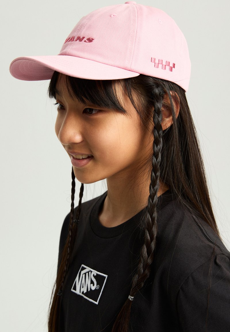 Rosa bomullskeps med broderad "VANS"-logotyp, böjd skärm och mönstrad sidodetalj, bärs med en svart skjorta som visar logotypen.