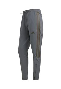 Sivé športové nohavice s elastickým pásom, ktoré sú ozdobené tromi kontrastnými tmavými pruhmi po stranách a zipsom na členku.