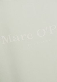Camiseta verde claro hecha de tela suave que presenta texto blanco: "Marc O'P" y "EST. EN ESTOCOLMO", con un diseño simple y sin patrones.