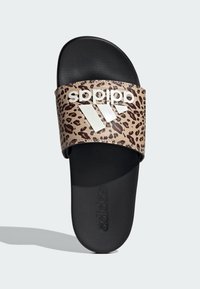 Sandały Adidas typu slide z paskiem w leopardzi wzór, z czarną gumową podeszwą i wyraźnym białym logo. Teksturowana górna część i gładka wkładka.