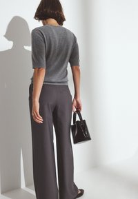 Pelēks īsām piedurknēm zeķubikses svārks, tumši pelēki plašas bikses un melna ādas rokassoma. Gluda tekstūra; vienkāršs dizains; nav redzamu rakstu.