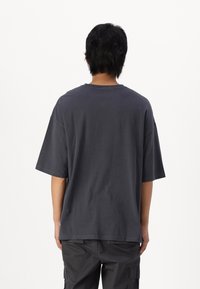 Grafisk T-shirt i mørkegrå, lavet af bomuld, med en afslappet pasform og korte ærmer. Har en rund halsudskæring og en ensfarvet bagside.