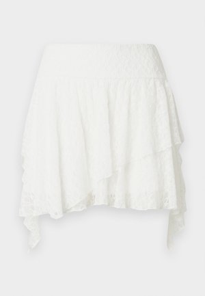 Jupe superposée en dentelle blanche avec large ceinture et ourlet asymétrique à bords pointus.