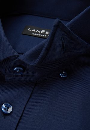 Granatowa koszula z kołnierzykiem o fakturowanej tkaninie, z zapięciem na guziki z przodu i metką z napisem "LANCER" w kolorze czarnym. Niebieskie guziki z motywem kwiatowym.