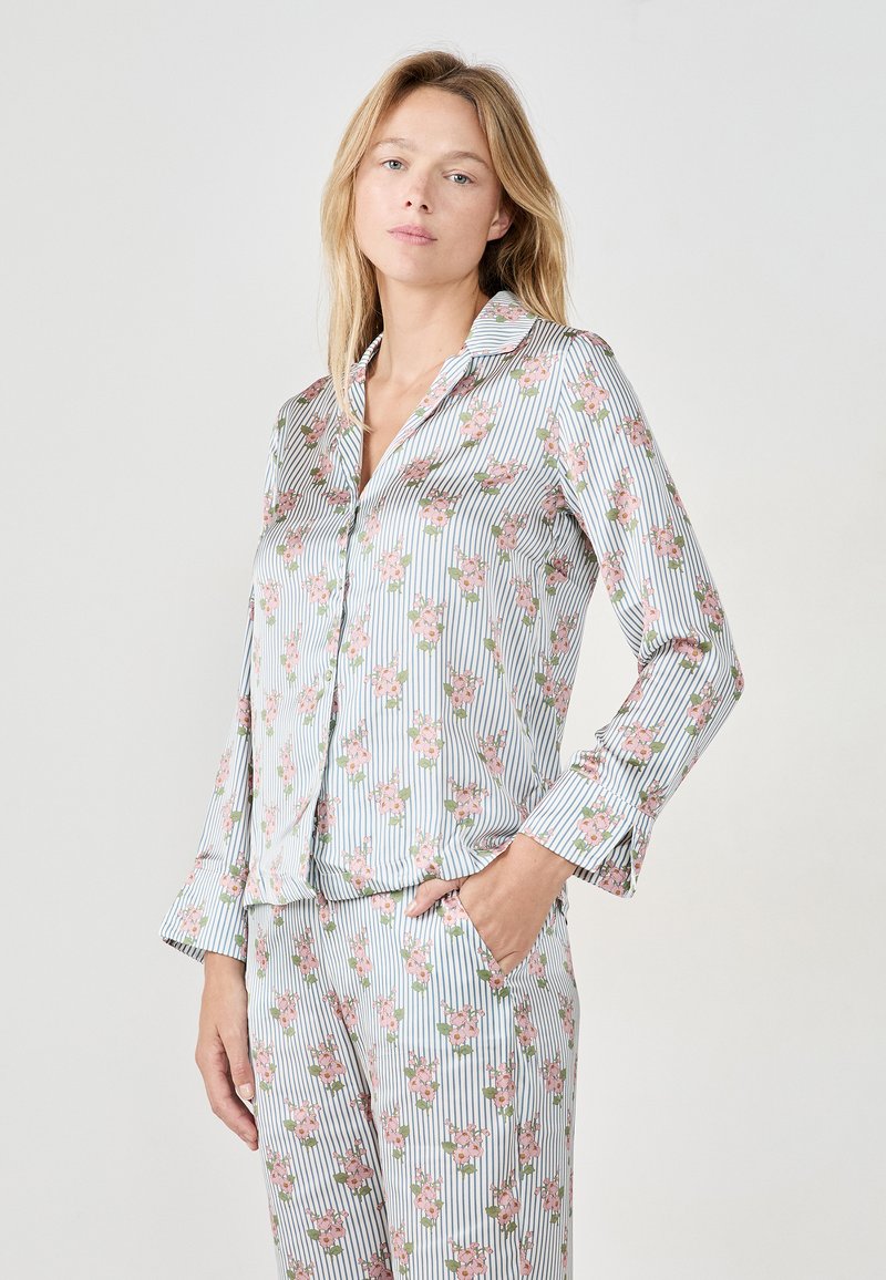 Conjunto de pijama a rayas en azul claro con patrones florales en rosa, que incluye una camisa con cuello y pantalones sueltos con puños y bolsillos.