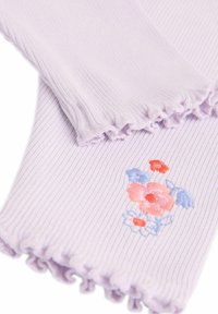 Lila bordázott anyagú karmelegítő fodros szélekkel, rózsaszín, kék és piros virágmintákkal hímezve. Puha tapintású, könnyű.