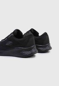 Zapatillas deportivas negras con tejido de malla y talón texturizado. Cuenta con un diseño de cordones y suela con patrón para un mejor agarre. Presente la marca en el lateral.
