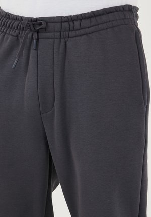 Donkergrijze sweatpants met een elastische tailleband, verstelbaar koord en zijzakken. Gemaakt van zachte, gladde stof met een relaxte pasvorm.