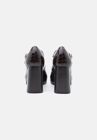 Černé lakované kožené lodičky na vysokém podpatku s texturou krokodýlí kůže, s čtvercovými blokovými podpatky a nastavitelnými kotníkovými řemínky.