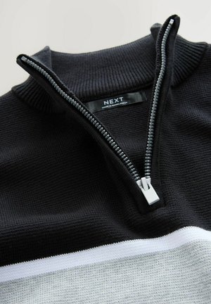 Black knit sweater with a white and light gray horizontal stripe, featuring a partially unzipped silver zipper and a ribbed collar.
