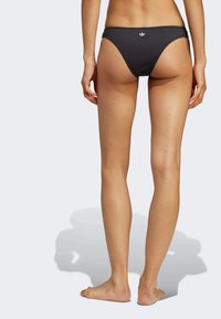 Black bikini bottom featuring a low-rise design, made from smooth material, with a small white logo on the back.