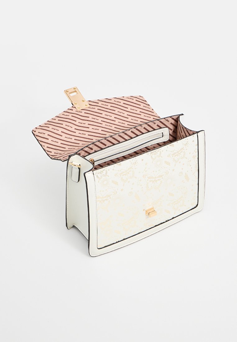 Sac à main blanc avec un motif floral texturé, des bords noirs et un fermoir doré. L'intérieur est doublé de rose avec le logo de la marque en répétition et une poche zippée.