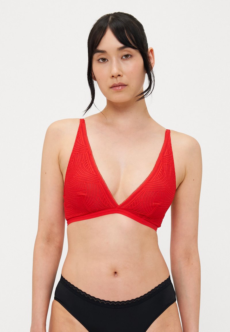 Piros bralette, háromszög alakú, texturált mintázattal, vékony pántokkal és sima derékrésszel. Fekete, magas derekú alsóneművel párosítva.