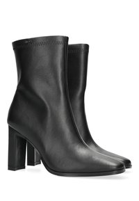 Czarne skórzane botki za kostkę o eleganckim fasonie, szpiczastych noskach i wysokim, masywnym obcasie. Wykończone przeszyciem wzdłuż górnej krawędzi.