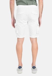 Pantaloni cargo bianchi realizzati in cotone, con due tasche laterali e due tasche posteriori. Presentano un orlo appena sopra il ginocchio e una vita piatta.