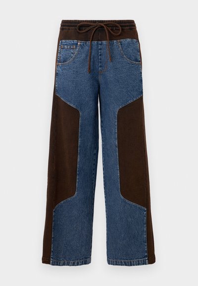 Pantalons à jambes larges avec un design en matériaux mixtes comprenant du denim bleu et des patchs en tissu marron, une taille élastique et un cordon de serrage.