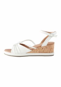 White wedge sandals with a cork heel, featuring a knotted front design, buckle ankle strap, and smooth leather texture.