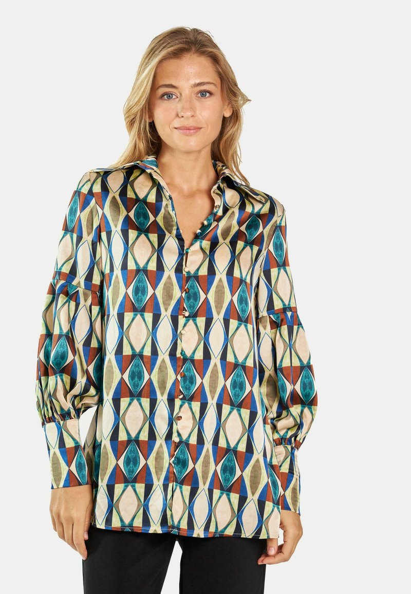 Blusa multicolor con un patrón geométrico en tonos verde azulado, rojo y beige. Hecha de una tela suave con un corte relajado y cierre de botones.