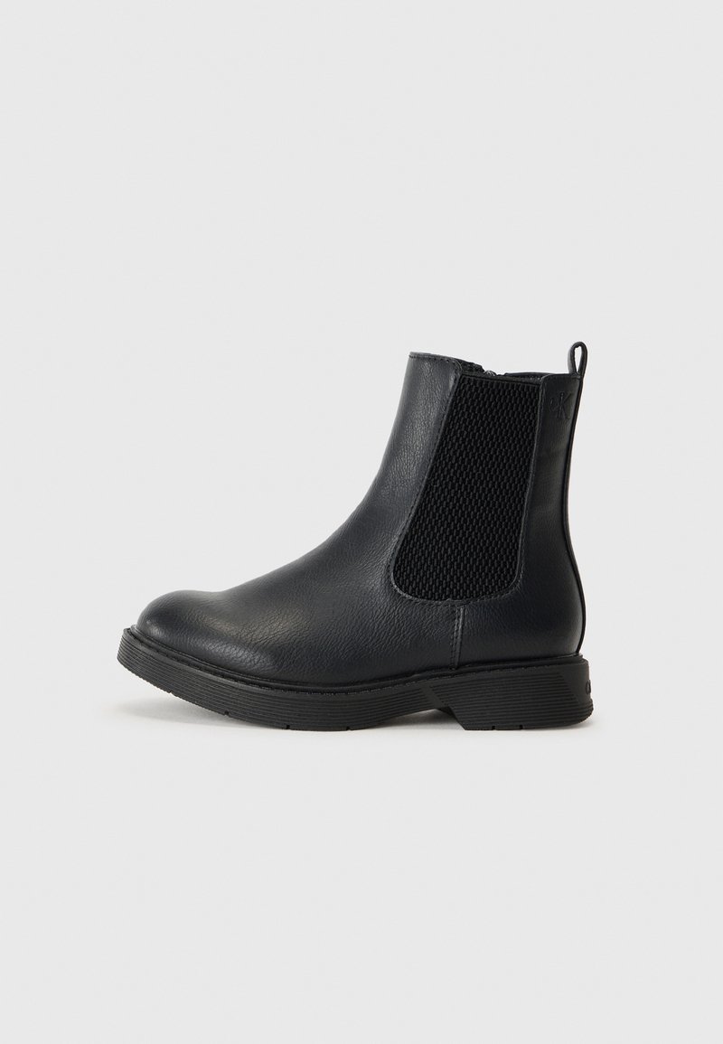 Bottine noire en cuir avec des panneaux latéraux élastiques, bout rond, tige texturée et petit talon en caoutchouc. Dotée d'une languette à l'arrière.