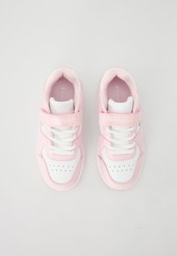 Baskets de sport roses et blanches avec une finition lisse semblable au cuir, comportant une sangle à boucle, des lacets et des détails perforés.