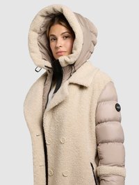 Vatteret jakke med cremefarvet shearling-yderside og beige polstrede ærmer, med en stor hætte, dobbeltradet lukning foran og sidelommer med lynlås.