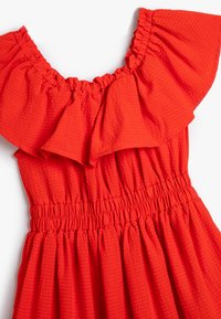 Rotes Kleid mit Rüsche an der Schulter, strukturiertem Stoff und gerafftem elastischem Bund. Verfügt über einen ausgestellten Rock mit gleichmäßigen Falten.