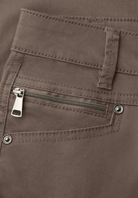 Close-up of brown fabric pants pocket with silver zipper, belt loop, and two metal rivets on stitched seams.