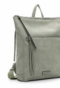 Zaino verde in pelle sintetica con apertura superiore con zip, spallacci regolabili e tasca frontale con zip. Presenta un design elegante e minimalista con accenti laterali.
