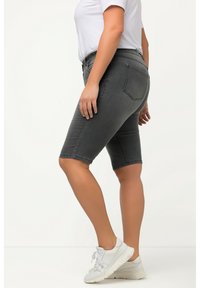 Shorts en denim gris au design ajusté, de longueur mi-cuisse, avec poches arrière et une texture lisse, accompagnés de baskets blanches et d'un t-shirt blanc uni.
