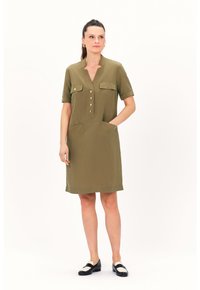 Abito verde oliva a maniche corte con scollatura a V, chiusura frontale con bottoni, due tasche sul petto e due tasche laterali, caratterizzato da una vestibilità rilassata e dritta.