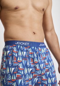 Boxer shorts blu con motivo di barche a vela multicolori. Vita elastica con il logo "JOCKEY". Tessuto leggero, dettaglio con chiusura a bottone.