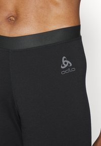 Schwarze Sportleggings mit glatter Textur, ausgestattet mit einem breiten Bund und einem kleinen grauen Logo am Oberschenkel.