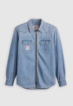 Heled sinine teksashirt pika varrukaga, terava kraega, esiseepega ja kahe rinnataskuga, millel on nupuga klapid ja logopatchid.