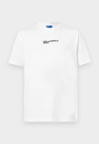 T-shirt de algodão branco com mangas curtas, apresentando uma impressão preta de "Karl Lagerfeld Jeans" no centro. Design clássico de gola redonda.