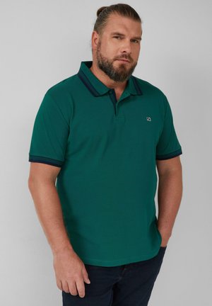 Green polo shirt with a collared neckline and navy blue accents on the collar and sleeves. Made of textured fabric, fitting closely at the body.