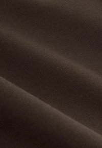 Material textil maro cu o textură netedă, având o ușoară elasticitate și o culoare uniformă. Nu sunt vizibile modele sau accente notabile.