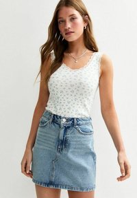 Top sin mangas con estampado floral y acabamento de encaje, combinado con una falda de mezclilla azul claro con cintura alta y bolsillos frontales.
