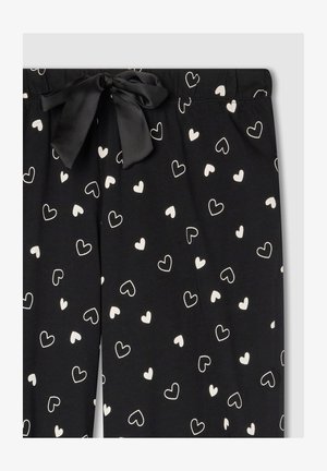 Pantaloni a pigiama neri con vita regolabile. Motivo a cuori bianche sparsi su tutta la stoffa. Realizzati in materiale morbido con una finitura opaca.