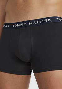 Boxer shorts noirs en tissu lisse avec une coupe ajustée. Dotés d'une ceinture élastique bleu marine avec le logo "TOMMY HILFIGER".