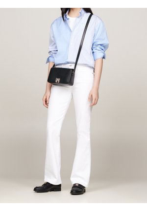 Musta nahkainen olkakassi hopeisella logolaatalla, yhdistettynä valkoisiin levenevälahkeisiin farkkuihin ja sinivalkoraidalliseen paitaan.