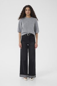 Maglione grigio a maniche corte abbinato a jeans di jeans nero a vita alta e gamba larga, con risvolti e cintura con fibbia argentata.