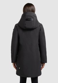 Must helekott, millel on kõrge krae ja üleriie suur kapuuts. Seljal asub logodetail ning külgedel on siledad taskud.