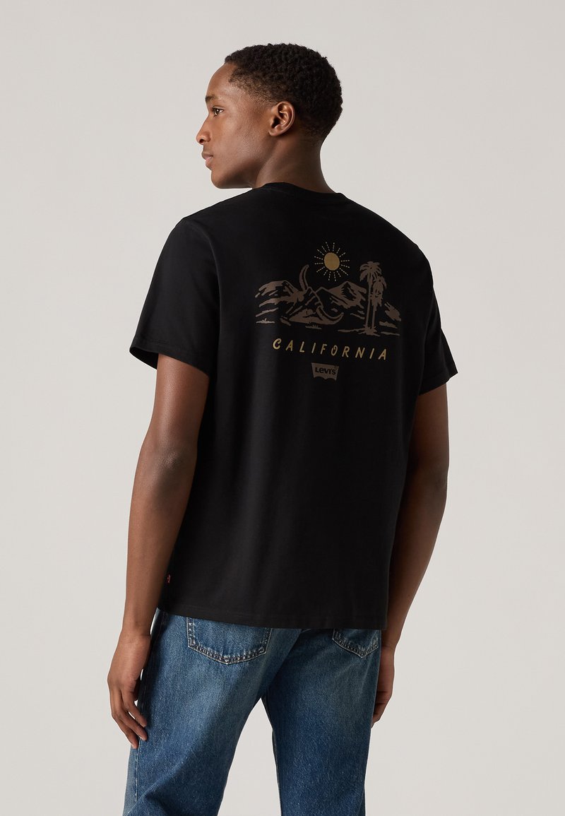 Sort bomulds T-shirt med et guldgrafik af bjerge og palmetræer med ordet "CALIFORNIA" nedenfor, stylet med rund hals.