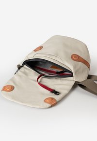 Beige Tasche aus strapazierfähigem Stoff mit braunen Lederakzenten. Verfügt über einen Umschlag, einen Reißverschluss und eine rote Innentasche. Verstellbarer Tragegurt ist enthalten.